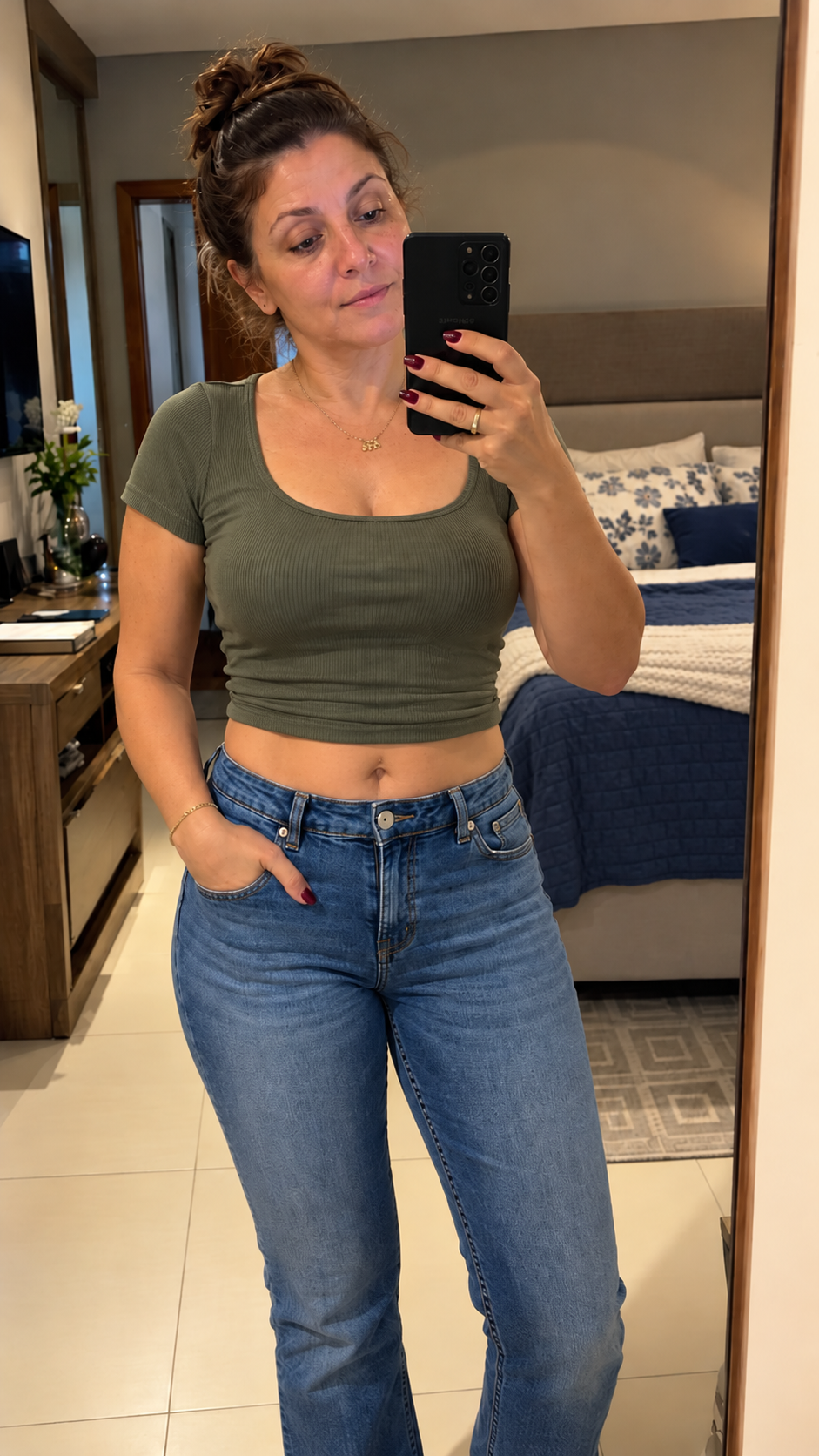 Carla depois: de calça jeans fechada, em frente ao espelho